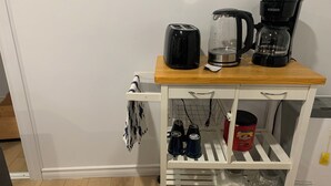 A kitchen with a white cabinet holding a coffee maker, a kettle, and a toaster. - Cozy basement place  (Kentville)