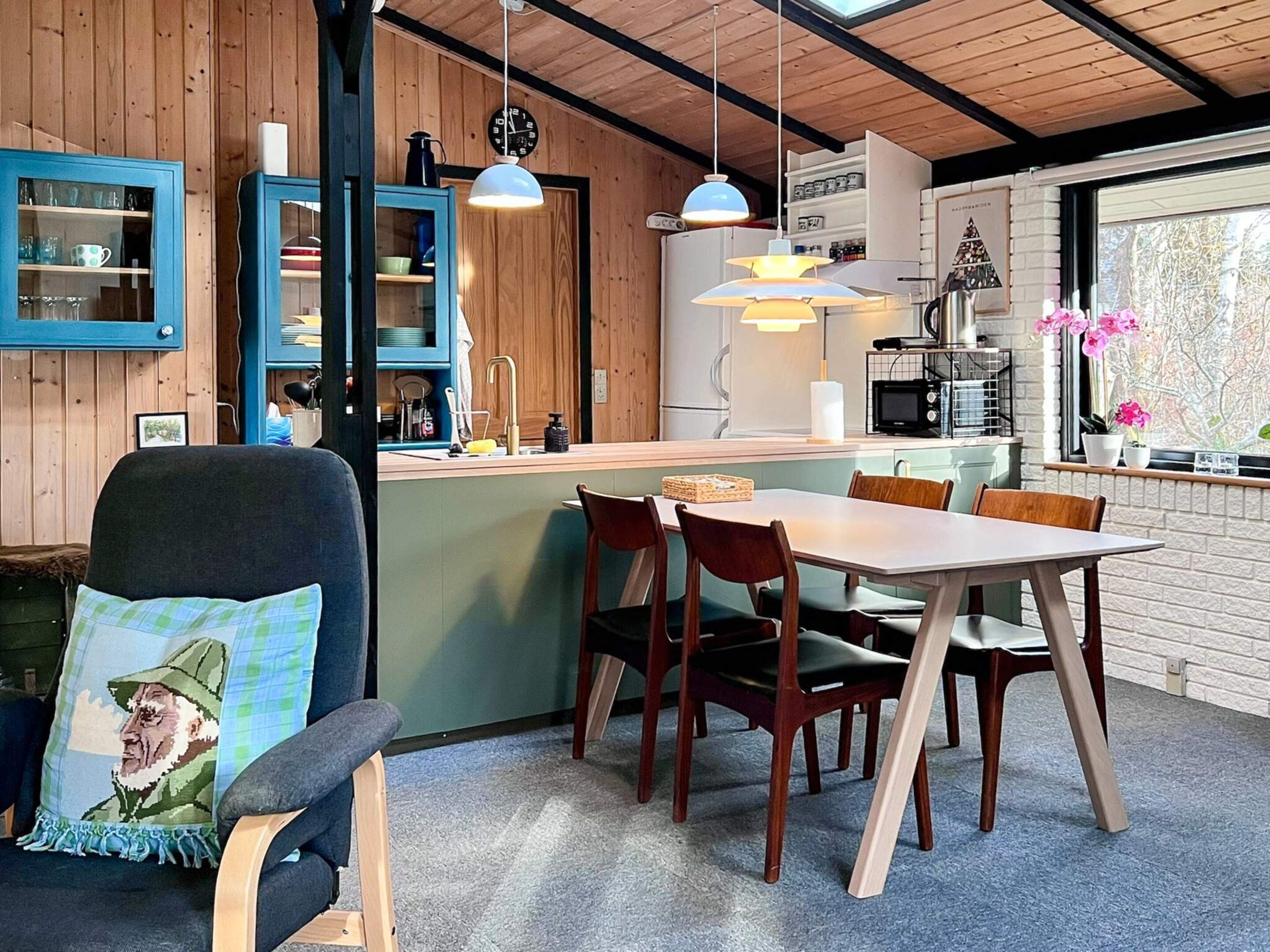 Una cocina acogedora con paredes de madera, un comedor con mesa y sillas, y una ventana con flores.