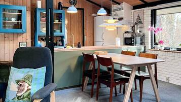 Una cocina acogedora con paredes de madera, un comedor con mesa y sillas, y una ventana con flores.