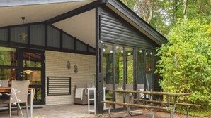 A covered patio area with outdoor seating, a brick floor, and potted plants.