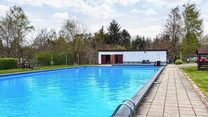 A rectangular swimming pool with a tiled deck and a metal ladder.