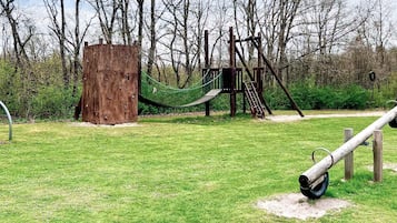 A playground with a wooden climbing structure, a rope net, and a tire swing.