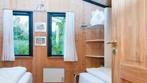 A room with two beds, wooden walls, a radiator, and a window with curtains. - 4 Person Holiday Home in Farvang (Farvang)
