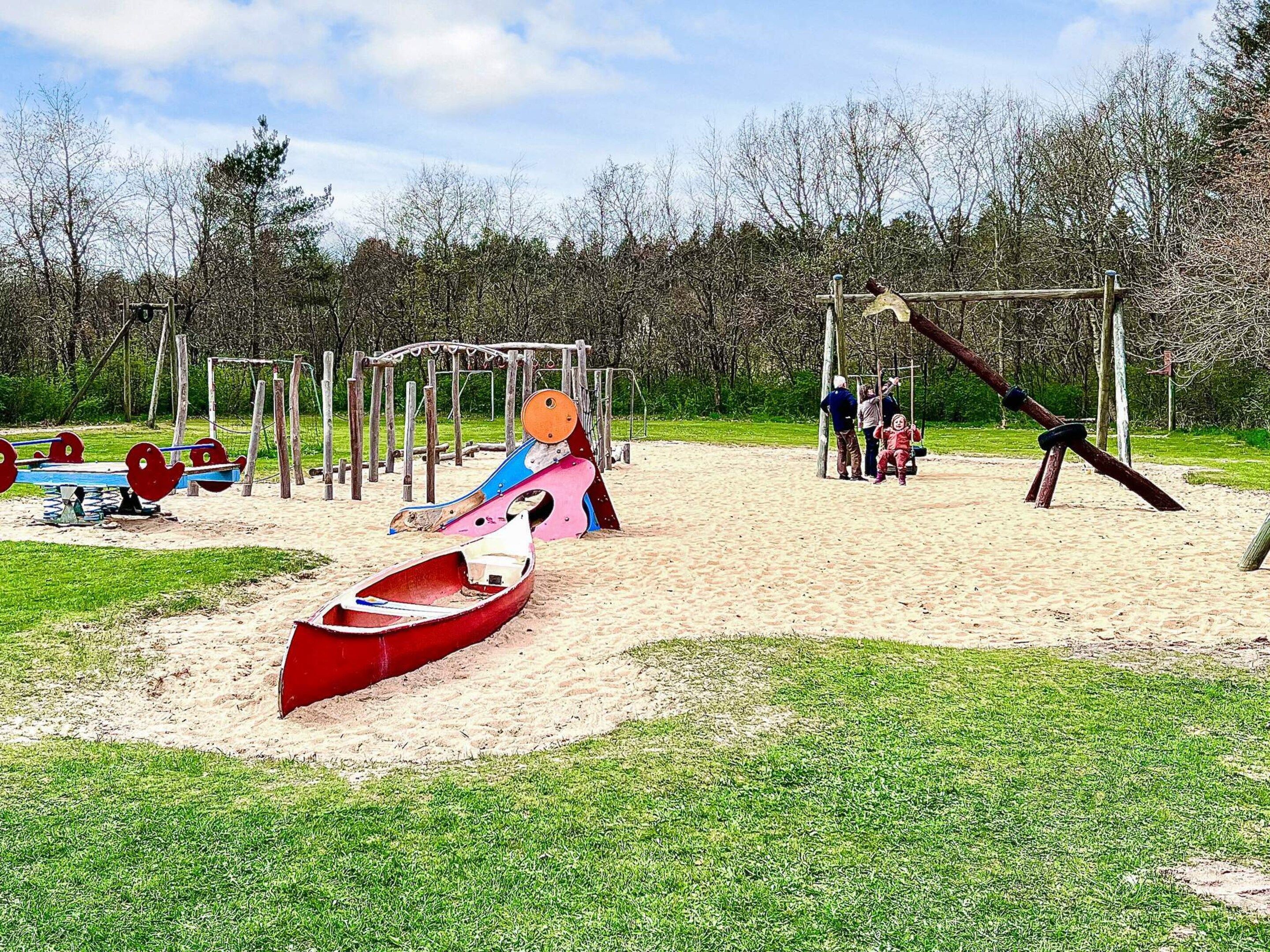 Un parque infantil con columpios, un tobogán y un sube y baja.