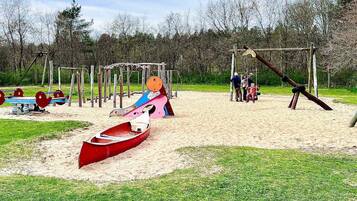 Un parque infantil con columpios, un tobogán y un sube y baja.