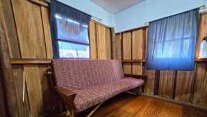 Una habitación con paredes de paneles de madera, un sofá estampado y suelo de madera.