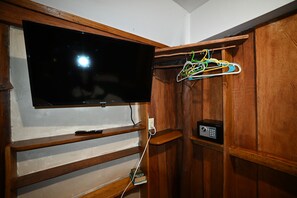 Une pièce équipée d’un téléviseur fixé au mur, d’étagères en bois et d’un clavier numérique pour le système de sécurité.