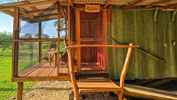 Una estructura rústica de madera con un porche cubierto y una puerta que dice 'Rustic'.