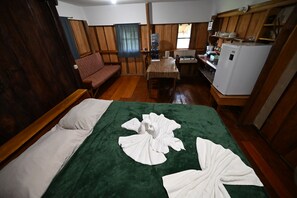 A room with a bed, a sofa, a table, and a kitchenette.