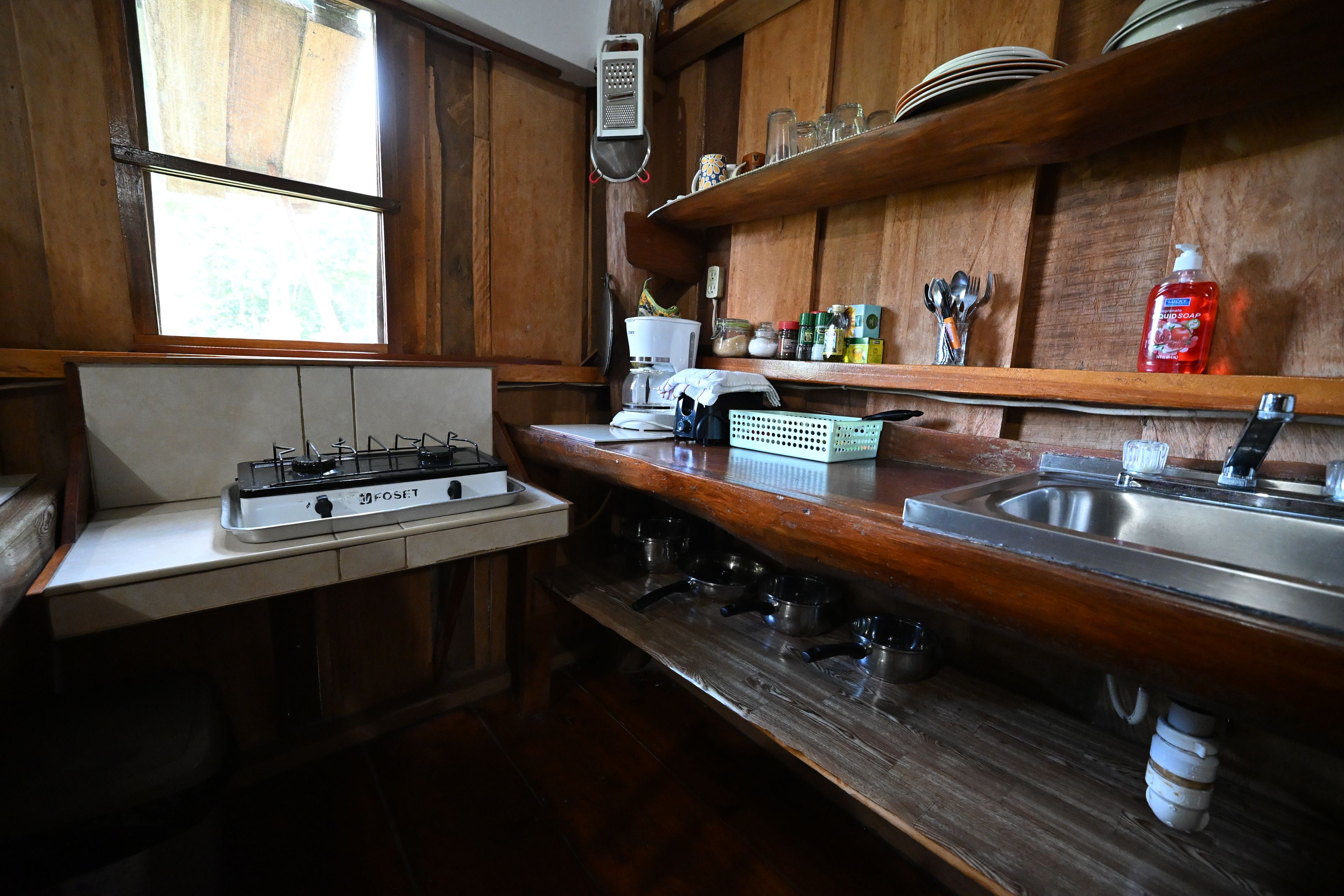 Una cocina con estufa a gas, un lavamanos y armarios de madera.