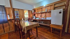 Un interior de madera con una mesa de comedor, sillas, un dispensador de agua y un refrigerador.