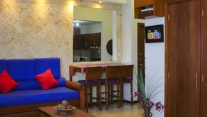 A living room with a blue sofa, red cushions, a wooden dining table, and a kitchen in the background. - MIRADOR DEL LAGUITO 404 (Cartagena)