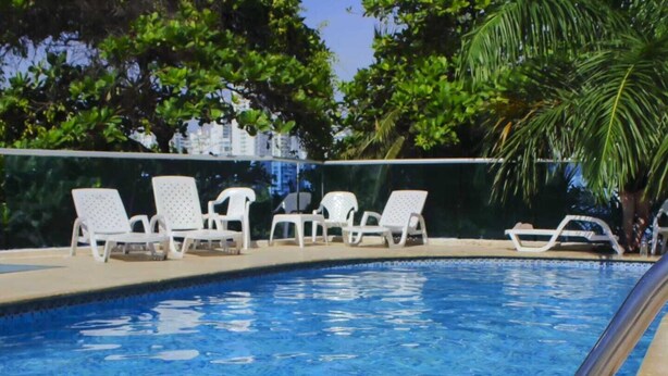 A swimming pool with white lounge chairs and a palm tree. - MIRADOR DEL LAGUITO 404 (Cartagena)