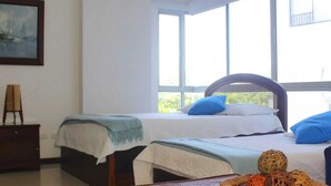 A room with two beds, a window, a painting, and a wooden chair. - MIRADOR DEL LAGUITO 404 (Cartagena)