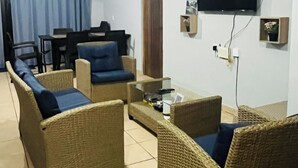 Un salon avec des meubles en osier, un téléviseur à écran plat et une petite table.