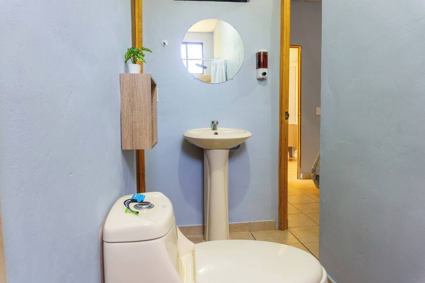 A bathroom with a toilet, sink, and mirror.
