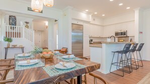 A modern kitchen with white cabinets, stainless steel appliances, and a small island with bar stools.