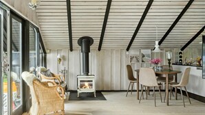 A cozy room with a fireplace, wicker furniture, and a dining area. - Beautiful home in Gedser with WiFi (Gedser)