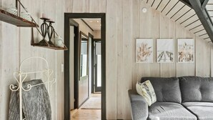 A cozy living room with a grey sofa, a wooden floor, and a view into another room. - Beautiful home in Gedser with WiFi (Gedser)