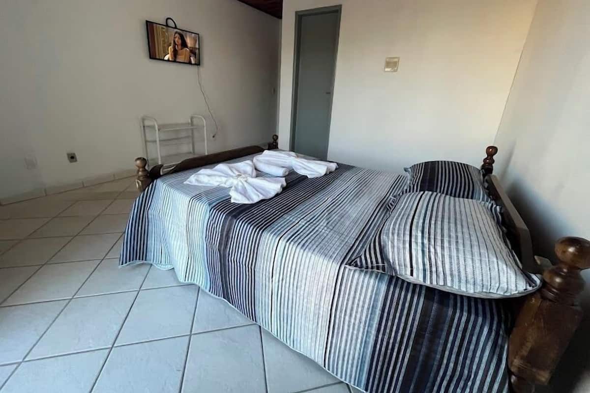 A bedroom with a bed, a television mounted on the wall, and a door.