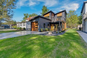 A modern two-story house with a garage, a well-maintained lawn, and a driveway. - The Winona Lake Chalet 1 (Winona Lake)