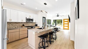 Una cocina moderna con armarios blancos, encimera de granito y una isla central con taburetes de bar.