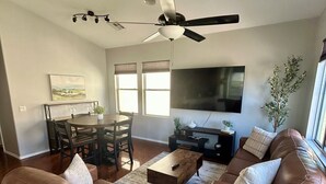 A living room with a brown leather sofa, a wooden coffee table, a TV, and a ceiling fan.