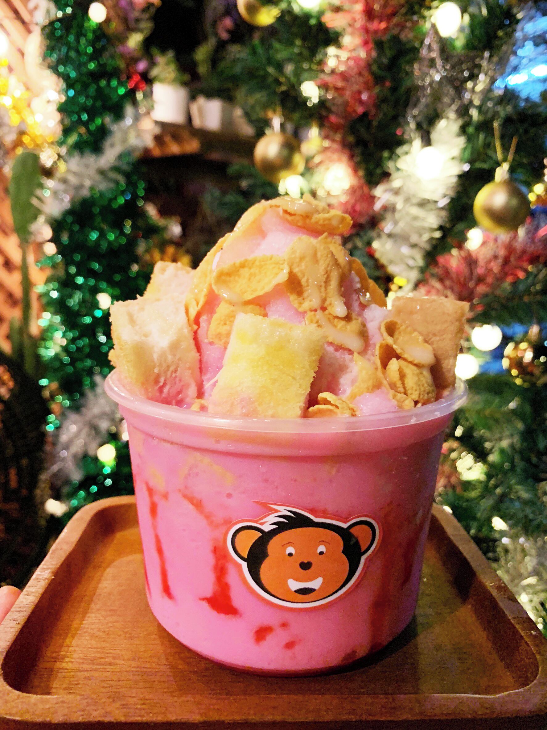 Eine rosa Tasse mit Bären-Aufkleber, gefüllt mit Eis und Getreideflocken, auf einem Holftablett platziert.