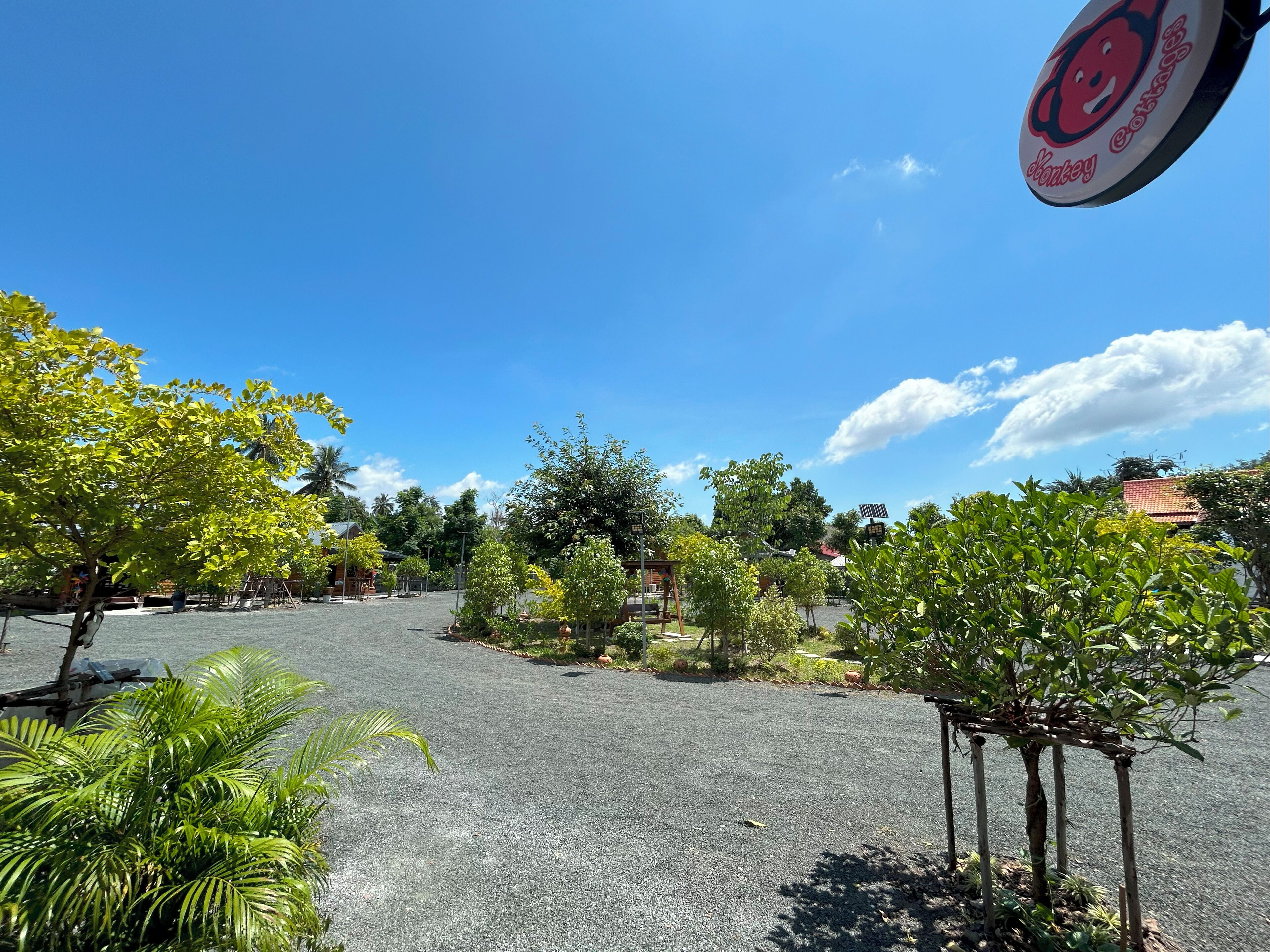 A parking lot with a sign for "Monkey Cottage" and surrounding greenery.