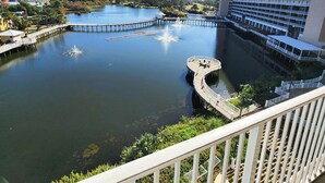A waterfront view from a balcony with a clear sky, a large hotel building, and a pier extending into the water. - Large 3 BD With Fountain Show Views on 5th Floor (Panama City Beach)