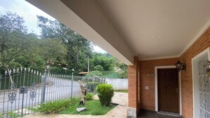 Un porche cubierto con un muro de ladrillo, una puerta y un portón metálico que da a la calle.