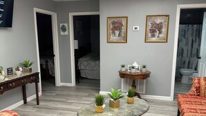 A room with a round glass table, red patterned sofas, a small wooden side table, and two framed paintings on the wall. - CLEARFORK CREEK LODGING & RV CAMPGROUND#4 (LaFollette)