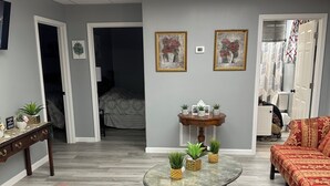 A living room with a sofa, a coffee table with plants, a TV, and a door leading to another room. - CLEARFORK CREEK LODGING & RV CAMPGROUND#4 (LaFollette)