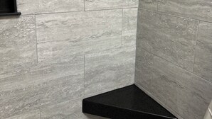 A bathroom with grey marble tiles, a black shelf, and a tiled floor. - CLEARFORK CREEK LODGING & RV CAMPGROUND#4 (LaFollette)