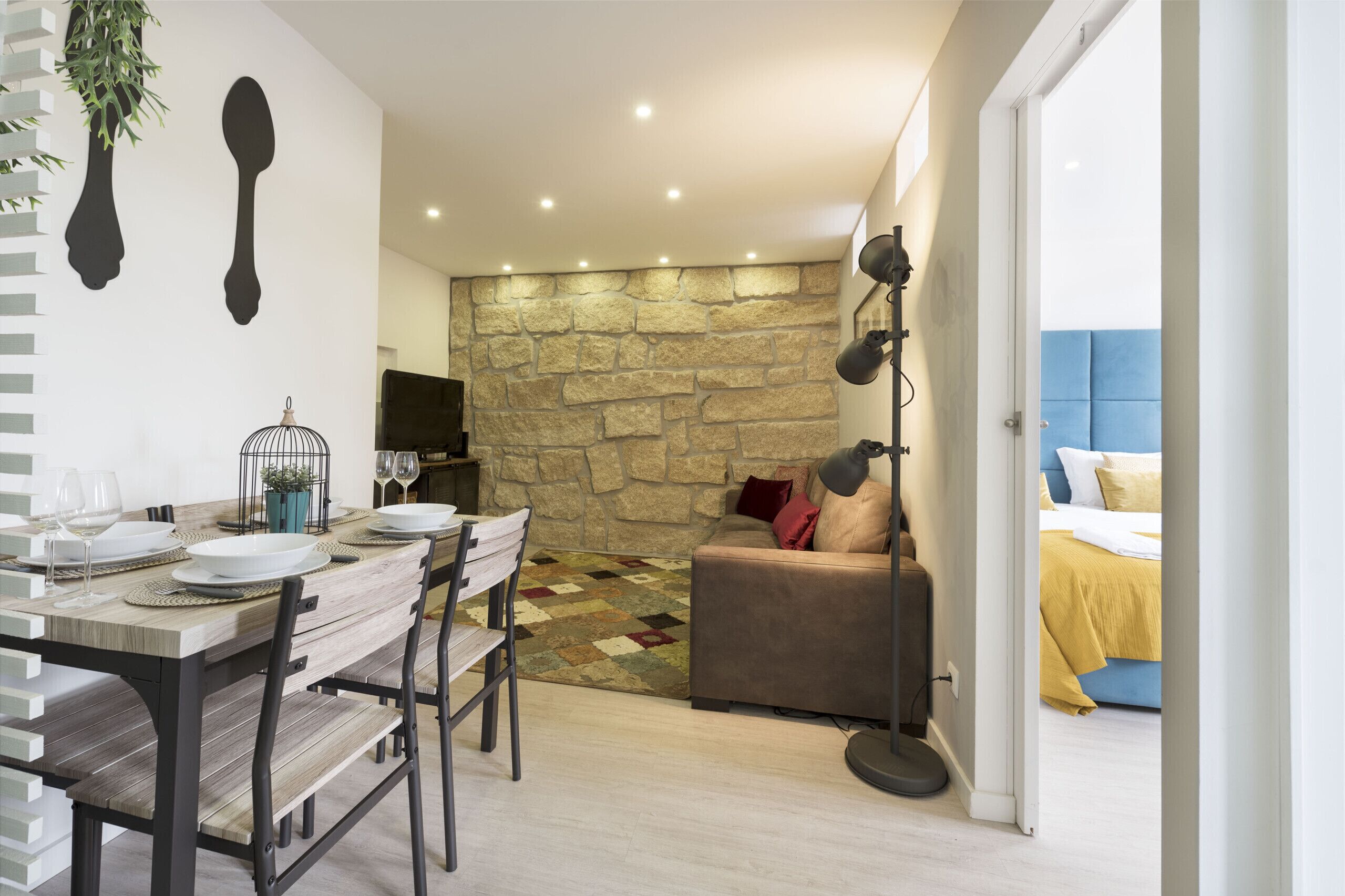 Un coin repas avec un mur en pierre, un canapé et un lit en arrière-plan.