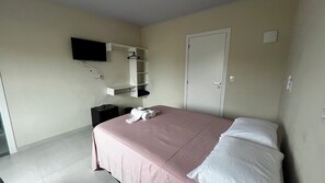 Ein Hotelzimmer mit einem Bett, einem an der Wand montierten Fernseher, einem Kleiderschrank und einer Tür.