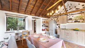 A dining area with a table set for four, a kitchen with a stone floor, and a wooden ceiling. - Holiday Home 'Estudio Bibi' with Mountain Views and Private Terrace (El Paso)