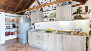 A kitchen with wooden cabinets, a refrigerator, a sink, and a countertop with a bowl of fruit and water bottles. - Holiday Home 'Estudio Bibi' with Mountain Views and Private Terrace (El Paso)