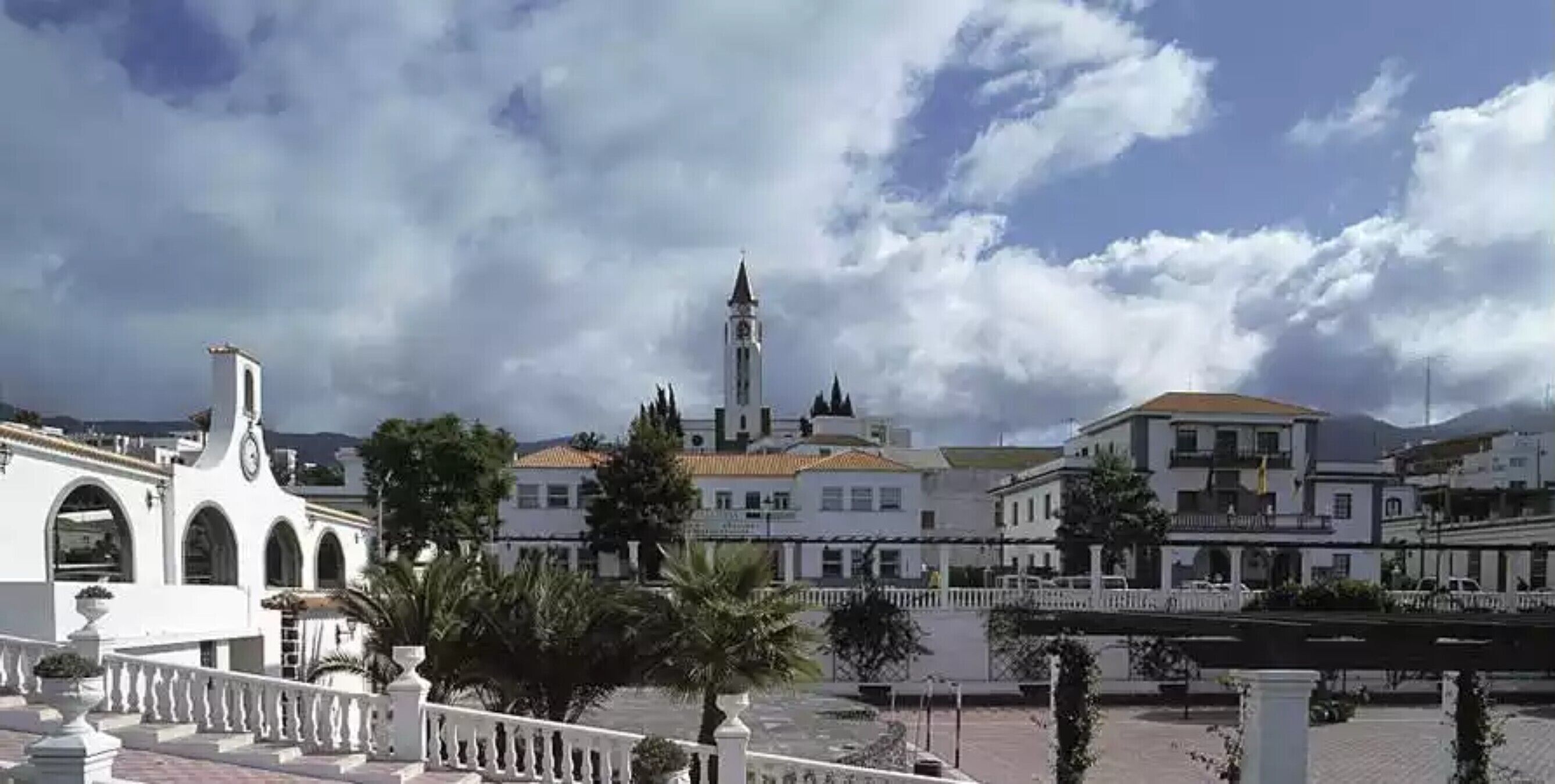 Une ville côtière aux bâtiments blancs, dotée d’un imposant beffroi et d’un pont.