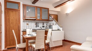 A kitchen with wooden cabinets, a dining table with chairs, a white refrigerator, and a microwave.