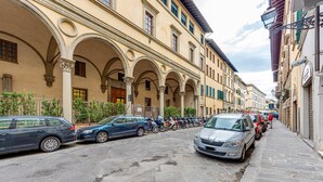 A street with parked cars and a row of arches.