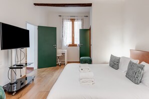Ein Hotelzimmer mit Bett, Fernseher, Schreibtisch und Stuhl.