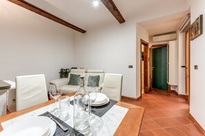 Een eetgedeelte met een tafel voor vier personen, een bank en een groene deur op de achtergrond.