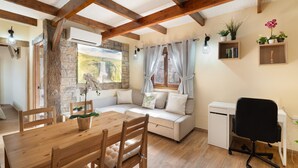 Une pièce chaleureuse avec une table à manger en bois, un canapé, un bureau avec une chaise et une petite kitchenette.