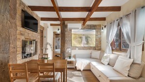 Un salon chaleureux avec une cheminée en pierre, des meubles en bois et une grande fenêtre agrémentée de rideaux.