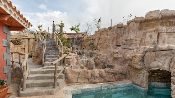 Un espace piscine agrémenté d’un mur en pierre, d’un escalier en bois et d’un sol carrelé.