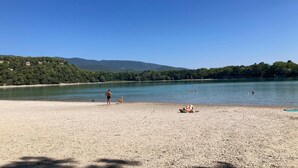 Une plage avec un ciel dégagé, une eau calme et un paysage vallonné en arrière-plan.