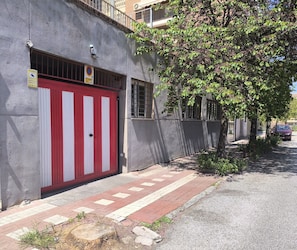 Ein Gebäude mit einer roten und weißen Garage sowie einer Überwachungskamera und einem Baum davor.