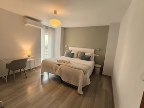 Un dormitorio con cama, mesita de noche, silla y lámpara colgante.
