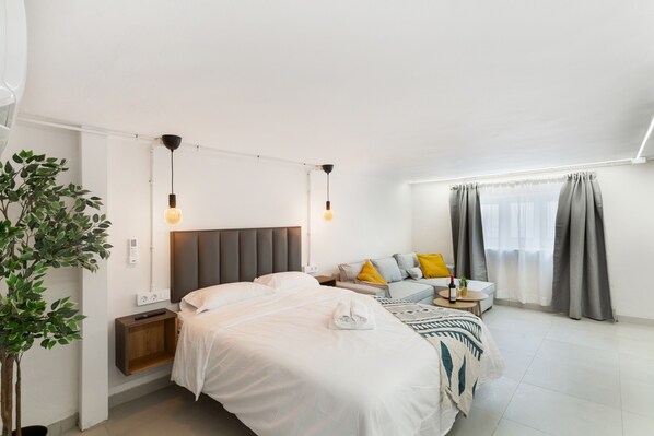 Una camera da letto moderna con un letto, un comodino, una lampada e una piccola pianta.